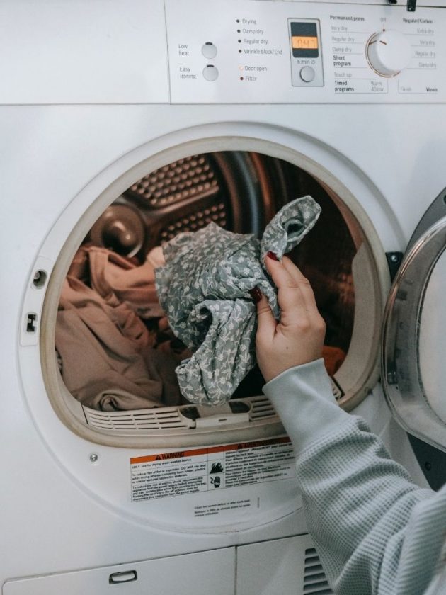 Girl putting clothes into washing machine