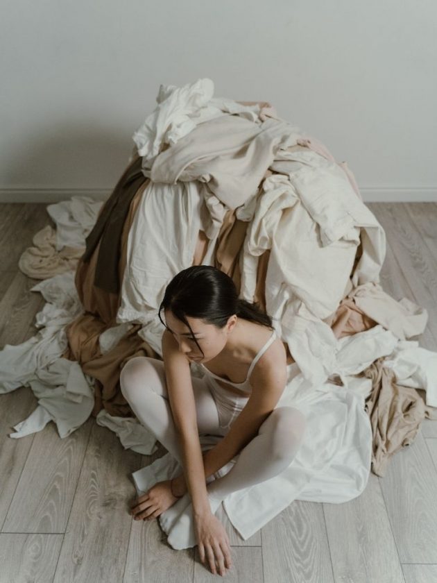 Woman with huge pile of clothes behind her with eco guilt