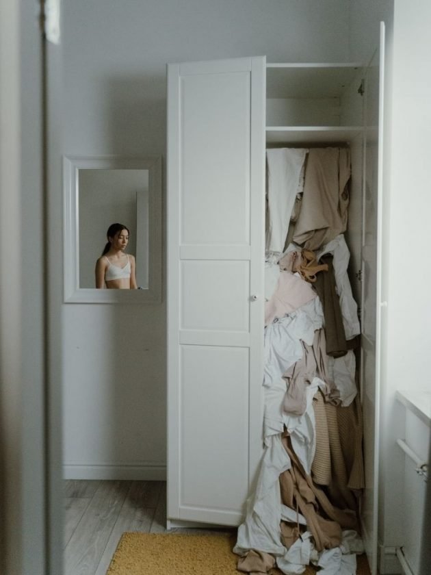 Woman staring at overfilled closet feeling guilty