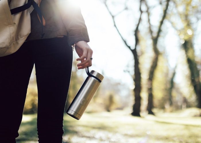 Woman with reusable water bottle walking in nature