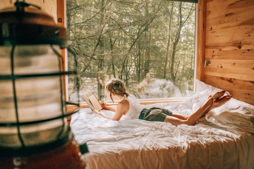 Elizabeth laying on bed reading a book inside Getaway Chicago cabin