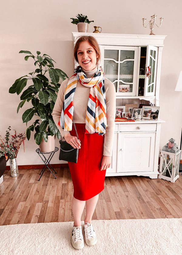 Girl wearing tan sweater, red skirt, and colorful scarf