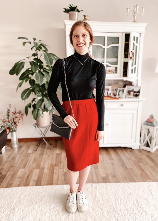 Girl wearing dark sweater, red skirt and sneakers