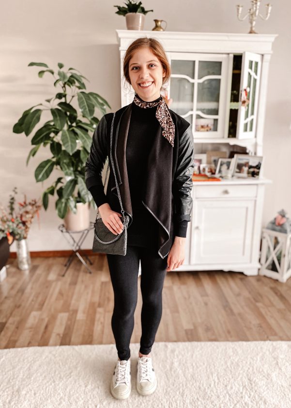 Girl wearing dark sweater, jacket and leggings with white sneakers