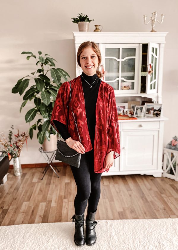 Girl wearing secondhand black sweater, red jacket and dark leggings