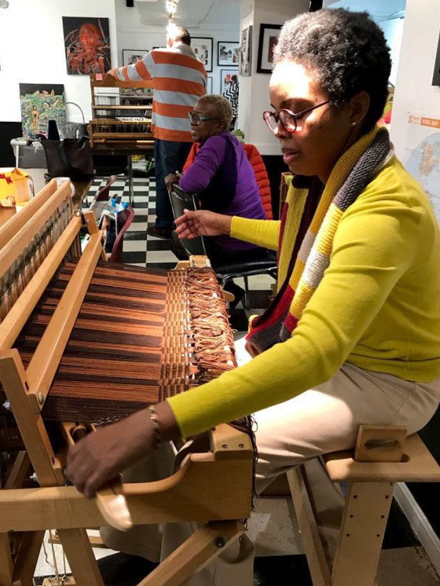 Karen Baker sitting at loom weaving