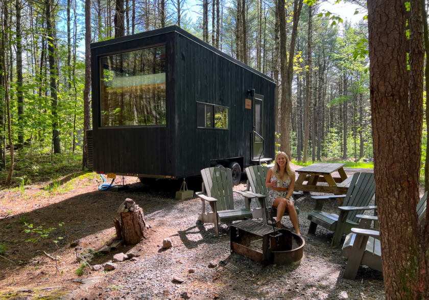 Alicia sitting on chair in front of Getaway eco cabin in the forest